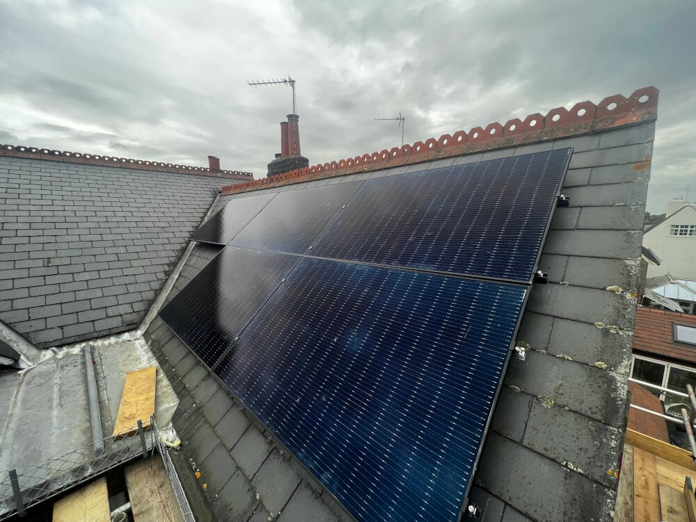 An all-black solar array on a slate pitched roof in Kent, photographed from the scaffold